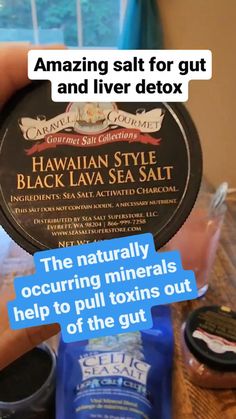 a person holding a jar of black lava sea salt next to some other items on a table