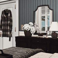 a room with a dresser, mirror and coat rack on the wall next to a bed