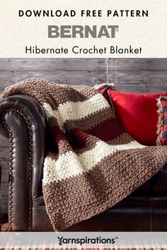 a crocheted blanket sitting on top of a leather couch next to a red pillow