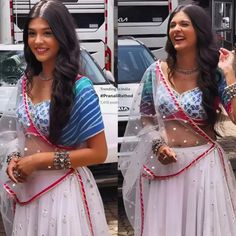 a woman in a white sari is smiling and holding her hand out to the side