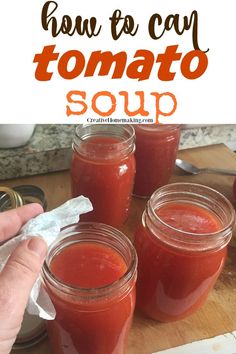 three jars filled with tomato soup sitting on top of a wooden table