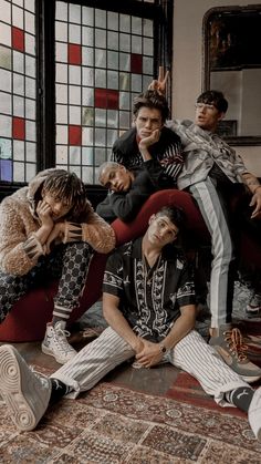 five young men sitting on the floor in front of stained glass windows, posing for a photo