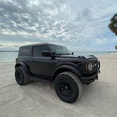 a black truck parked on top of a sandy beach