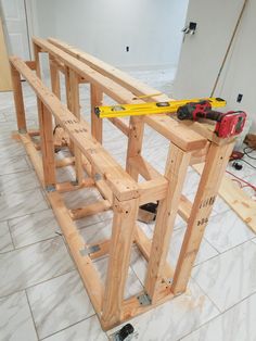 a wooden bench being built in a room with tools on the floor and construction equipment around it