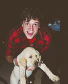 a young man is holding a puppy in his lap