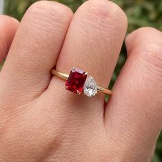 a woman's hand holding a red and white diamond ring