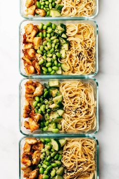 four glass containers filled with different types of pasta and veggies on top of a white table