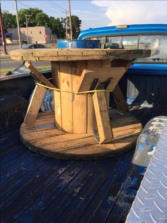 a wooden table sitting on the back of a blue pick up truck in a parking lot