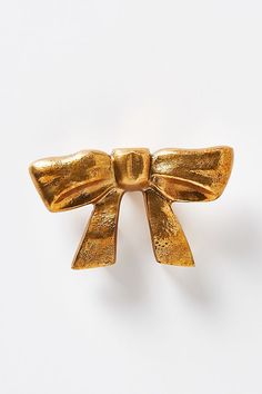 a gold bow brooch sitting on top of a white surface