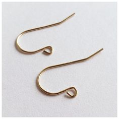 two pairs of gold - plated metal hook earrings on white background, close up