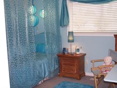 a baby's room with blue curtains and furniture