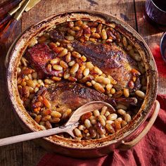 a pot filled with beans and meat on top of a wooden table