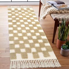 a beige and white area rug with tassels on the floor in front of a window