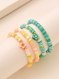 four different colored bracelets sitting on top of a white table next to a window