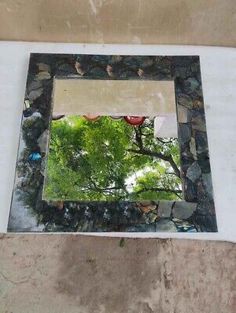 there is a mirror on the side of a wall with rocks and trees in it