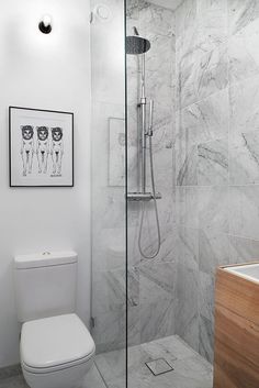 a bathroom with marble walls and flooring, including a walk in shower next to a toilet