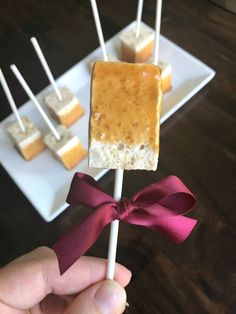 a hand holding a marshmallow lollypop on a stick with a bow