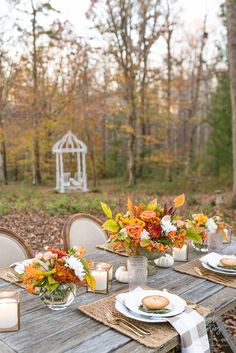 a wooden table topped with plates covered in flowers and vases filled with orange and white flowers