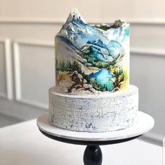 a three tiered cake decorated with mountains and lakes