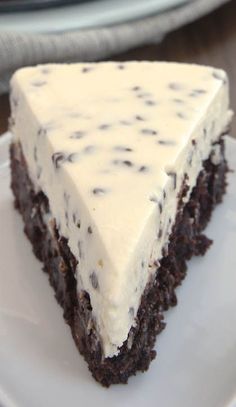 a slice of chocolate cake with white frosting sitting on top of a white plate