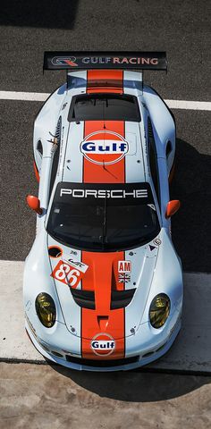 an orange and white race car parked on the street