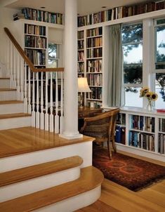 there is a staircase in the house with bookshelves on both sides and a table next to it