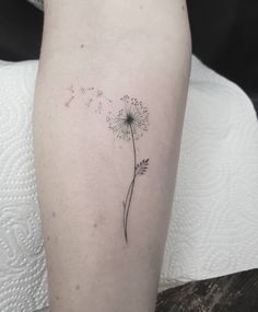 a small dandelion tattoo on the right thigh, with flying seeds coming out of it