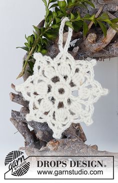 a crocheted snowflake hanging from a tree branch