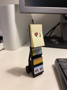 a small carton with cards attached to it sitting on a desk next to a keyboard