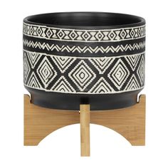 a black and white planter sitting on top of a wooden stand