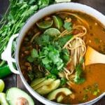 a white bowl filled with soup next to sliced cucumbers and parsleys