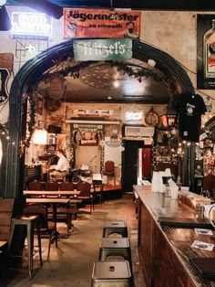 the inside of a restaurant with many tables and stools in front of an arched doorway