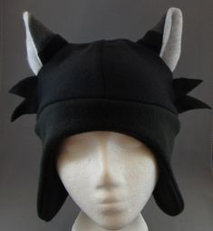 a white mannequin head wearing a black hat with horns on it's ears