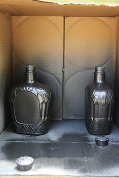 two black vases sitting inside of a cardboard box