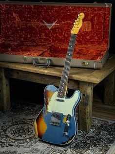 an electric guitar sitting on top of a wooden table next to a case and rug