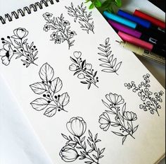 a notebook with flowers and leaves drawn on it next to markers, pencils and crayons