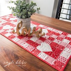 a table runner with the word love spelled out on it and a potted plant