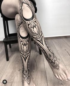 a woman with tattoos on her legs sitting in a chair next to a wooden floor