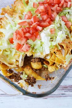 a glass casserole dish filled with taco salad and tortilla shells