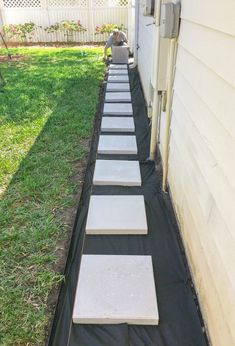 a long row of stepping stones on the side of a house next to a yard