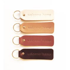 four leather key chains with the words welcome home and welcome home written on one side