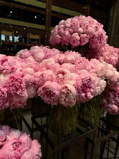 pink carnations in vases on display at a flower shop, ready to be sold