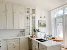 a kitchen with white cabinets and an island in front of a window that looks out onto the yard