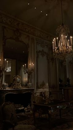 a chandelier hanging from the ceiling in a dark room with mirrors and furniture