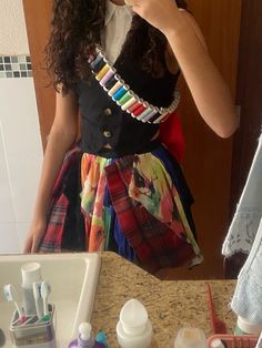 a woman taking a selfie in front of a bathroom mirror wearing a colorful dress