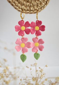 Add a touch of whimsy and elegance to any outfit with these stunning Pink Flowers Earrings. These earrings feature a beautiful cluster of delicate pink flowers that dangle gracefully from a gold-tone earring hook. Handcrafted with care, these earrings are made from high-quality materials, ensuring durability and longevity. The flowers are made from lightweight polymer clay and are adorned with delicate green leaves to give them a unique and eye-catching look. Measuring approximately 3 inches lon Delicate Drop Flower Earrings For Bridesmaid Gift, Feminine Handmade Flower Earrings, Handmade Feminine Flower Earrings, Delicate Handmade Dangle Flower Earrings, Feminine Drop Earrings With 3d Flowers, Handmade Flower Jewelry For Bridesmaid Gift, Whimsical Pink Earrings With Flower Charm, Handmade Flower Earrings As Feminine Gift, Handmade Feminine Flower Shaped Earrings