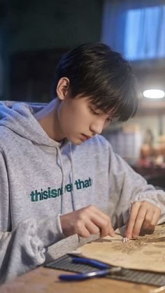 a young man sitting at a table working on something