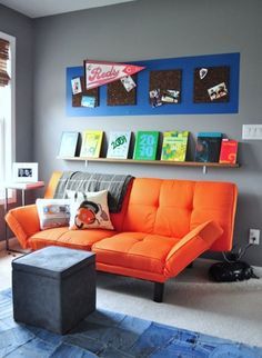 a living room with an orange couch and blue rug