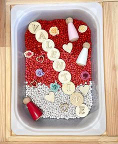 a container filled with lots of crafting items on top of a wooden table next to a wall