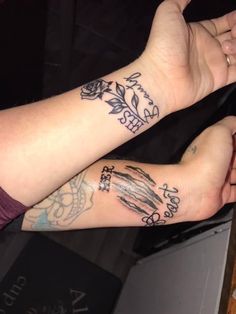 two people with tattoos on their arms are sitting next to each other and holding hands